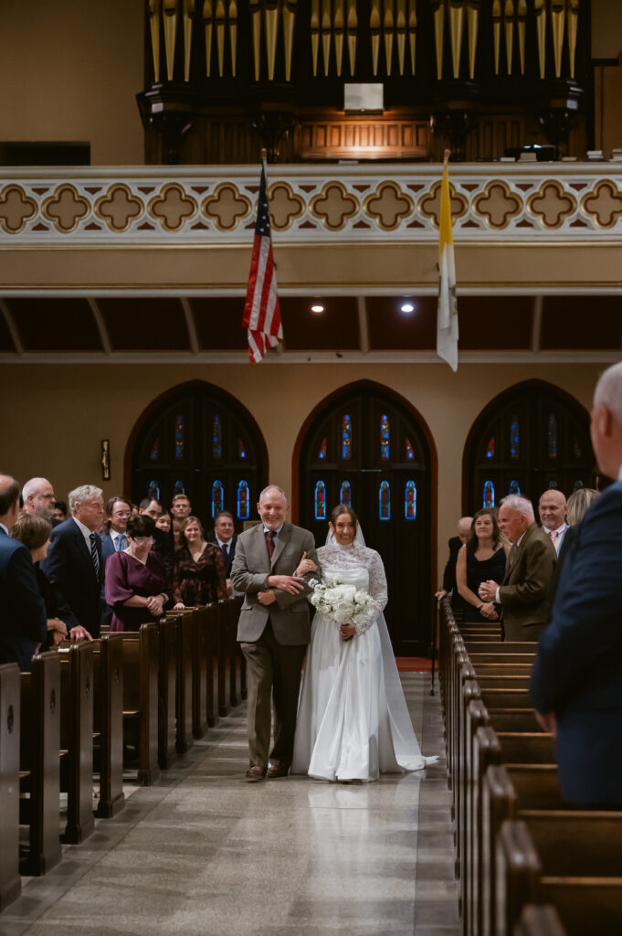 A Catholic Bride walks down the aisle to her Catholic Groom during the Catholic Wedding Mass