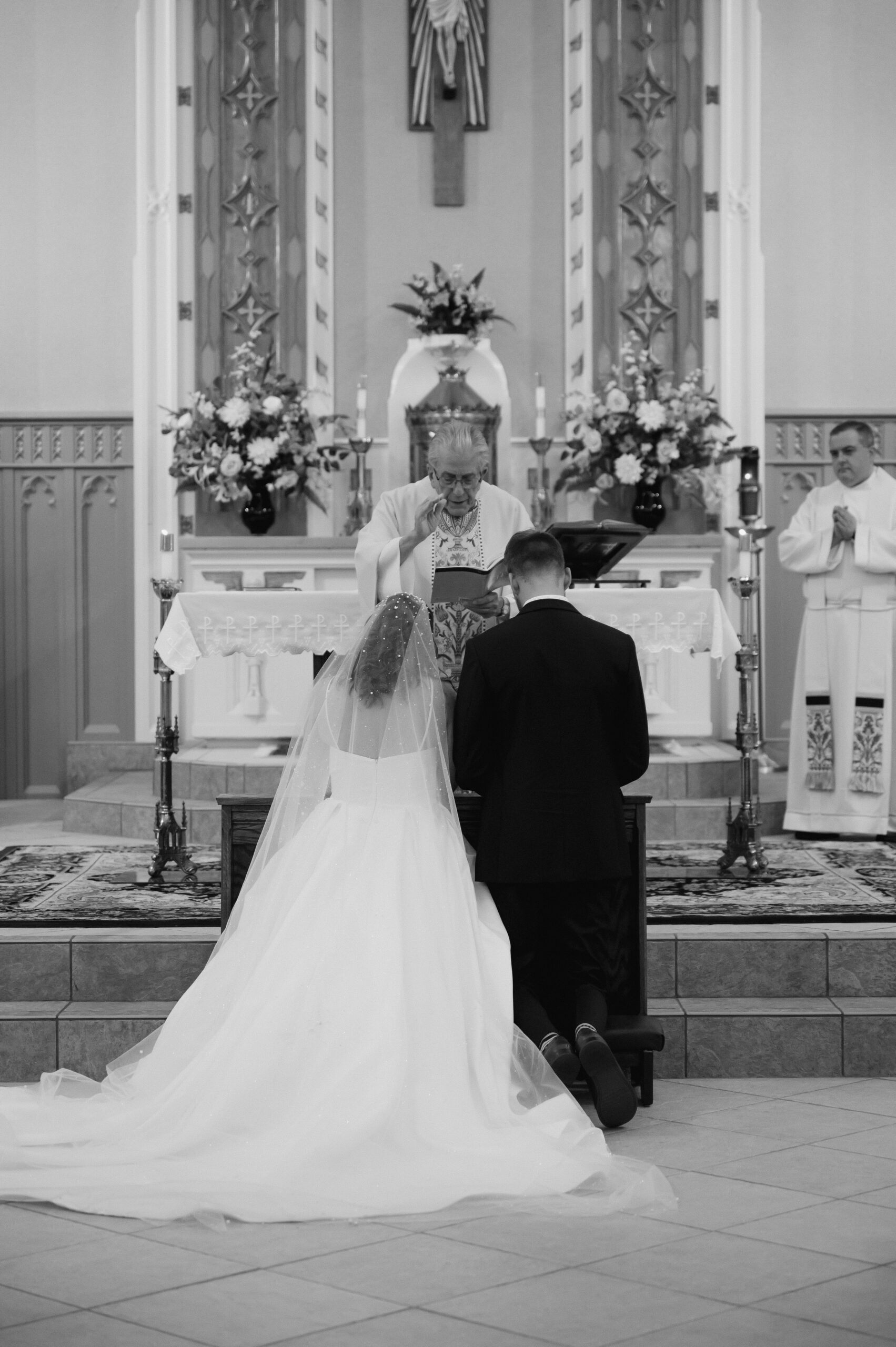 A priest blesses a Catholic Bride and a Catholic Groom during their Catholic Wedding Mass